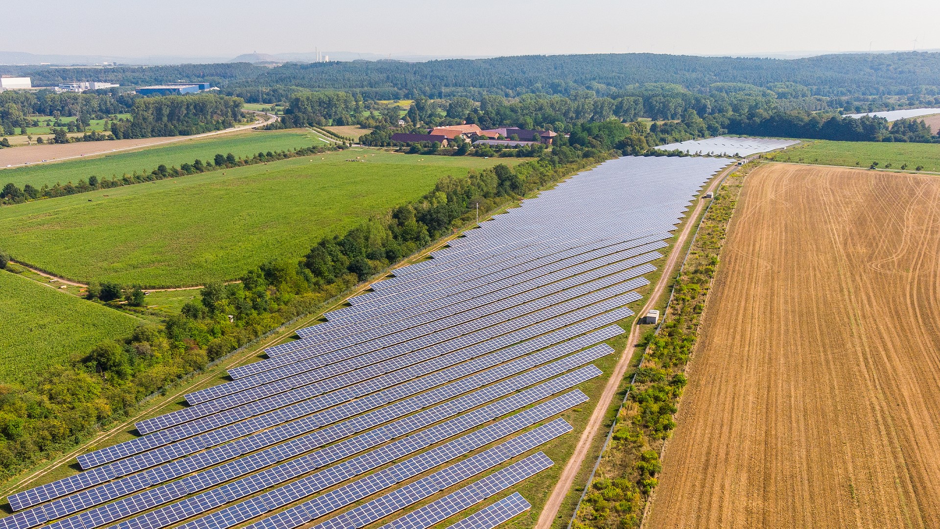 Luftaufnahme der Solaranlage Linslerhof, der im Hintergrund zu sehen ist.