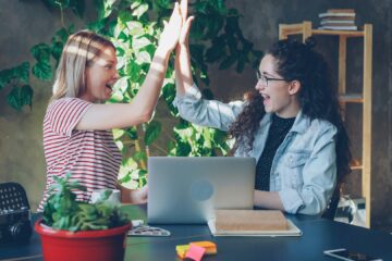 Zwei junge Frauen geben sich gegenseitig im Büro High Five