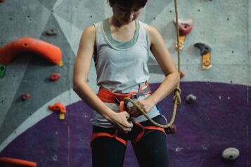 Frau mit Sicherheitsausrüstung für eine Kletterwand